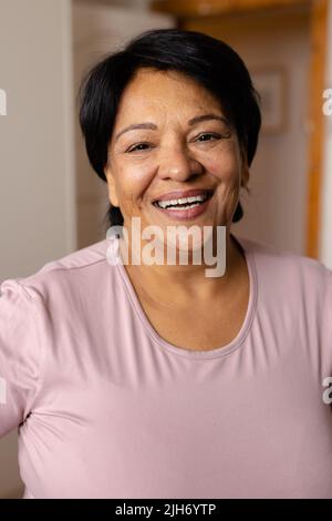 Close-up portrait of happy biracial mature woman with short hair laughing at home Stock Photo