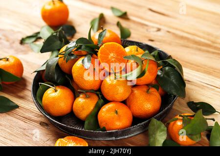 Fresh  Small Mandarin Oranges Fruit or Tangerines with Leaves on a RUstic Tray on Wooden Table Stock Photo