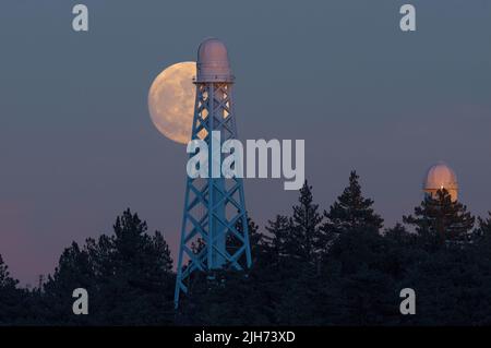 Full moon rising behind the 150 ft Solar Tower Telescope at Mt Wilson Observatory in the San Gabriel Mountains, California. Stock Photo