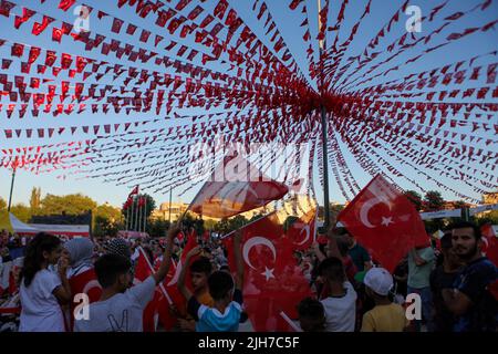 Gaziantep, Turkey. 1st Jan, 2000. Gaziantep, Turkey. 15 July 2022. Turkish citizens gather in the Democracy Square of the Turkish city of Gaziantep raising the national flag and listening from a screen to the Turkish president remembering the bravery of the country during the July 15, 2016 attempted coup. President Recep Tayyip ErdoÄŸan delivered a speech at a ceremony in Istanbul's Saraçhane Square to commemorate those killed during the July 15, 2016 defeated coup. Since the Coup attempt, July 15 has been designated as the ''Democracy and National Unity Day' (Credit Image: © Zakariya Yahya Stock Photo