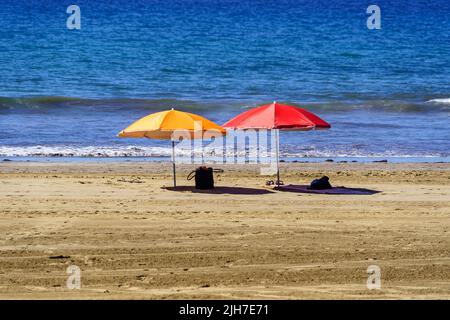 two solitary umbrellas on the beach of Maspalomas area dorada in the canary islands. Spain. Stock Photo