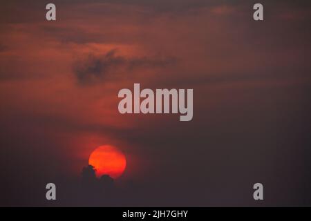 An orange sun disk sets in to cloud at dusk. Kanagawa, Japan. Stock Photo