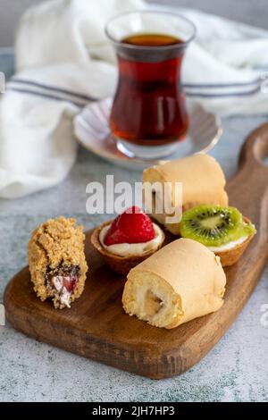 Delicious snacks. Roll cake, chocolate chip cake and fruit tart on a stone background. close up Stock Photo