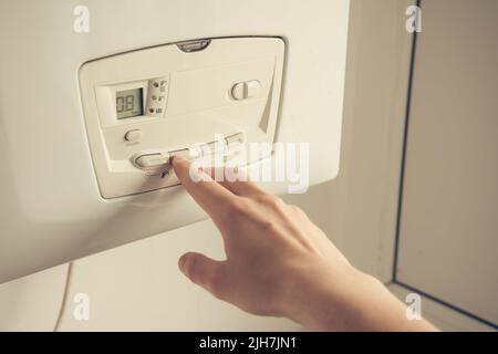 Male hand setting temperature on a heating boiler construction. Stock Photo