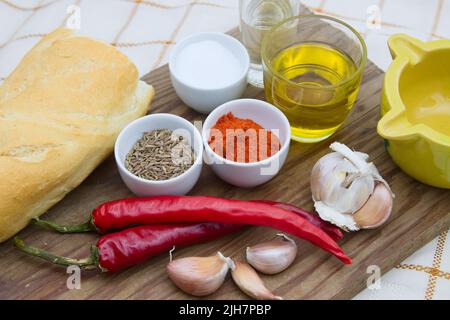 Close-up of a table with garlic, paprika, salt, oil, chilli pepper, bread to prepare the Canarian and Spanish sauce the red mojo picón Stock Photo