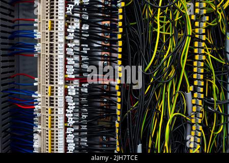 Electrical wiring harnesses connected to terminals in the control cabinet of an industrial machine. Cable ends marked with descriptions Stock Photo