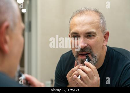Middle-aged handsome man using razor in bathroom Stock Photo
