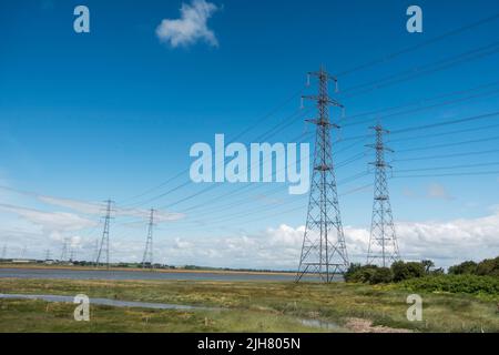 A pair of tall electricity pylons carrying cables across the Lune estuary near Lancaster, England, UK Stock Photo