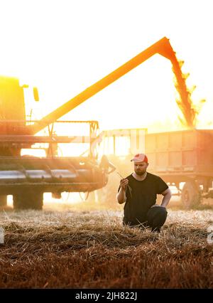 Satisfied farmer standing by harvester Stock Photo