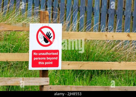No unauthorised persons beyond this point sign fitted to a wooden fence Stock Photo
