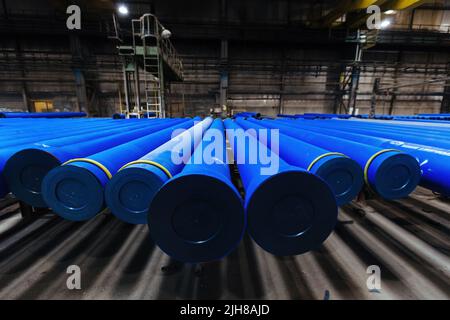 New blue colored cast iron pipes with caps for pipeline construction in warehouse. Stock Photo