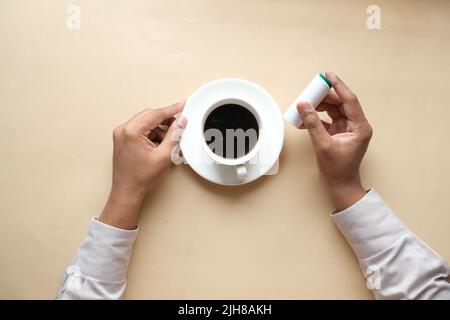 young man putting artificial sweetener in tea, Stock Photo