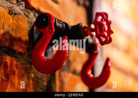 Close up red huge big hooks hanger or rack for clothing on brick stony wall in cafe bar pub cloakroom. Steampunk style design element Stock Photo