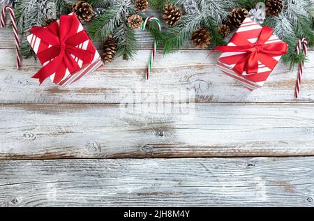 Christmas and New Year holiday concept with snow covered fir branches, traditional stripe gift boxes, candy canes and silver gold pine cones on white Stock Photo