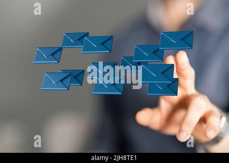 A businessman on a blurry background touching a floating render of email icons Stock Photo