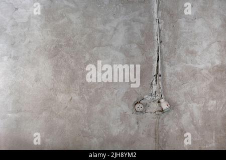 Rustic electrical socket on old limewashed plaster wall, indoor architecture detail, grunge background Stock Photo