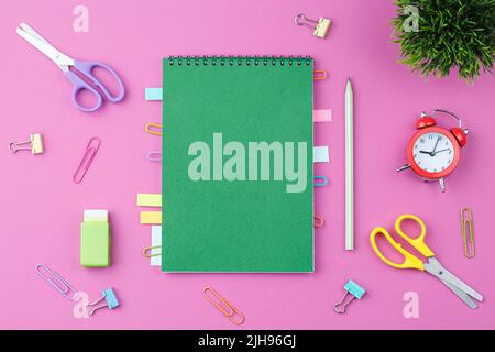 Green notepad with stationery on a pink background Stock Photo