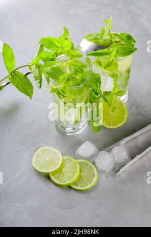 Mojito cocktail on a gray background. Two glasses of cocktail with mint, lime and ice. Bar tools and ingredients for cocktail Stock Photo