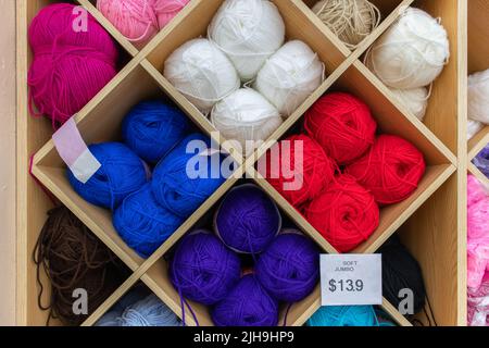 stack of colorful worsted wool yarn batch in square spaces of a shelf or rack in a store Stock Photo