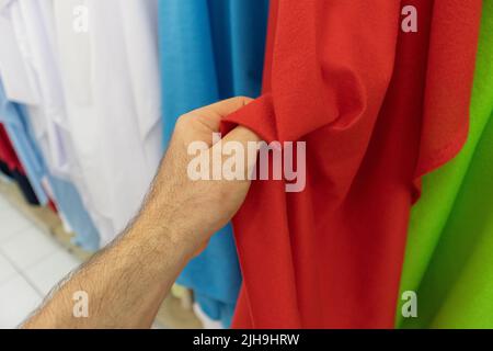 Hand of a young man touching a piece of a red cloth fabric in a cloth store in Mexico Stock Photo