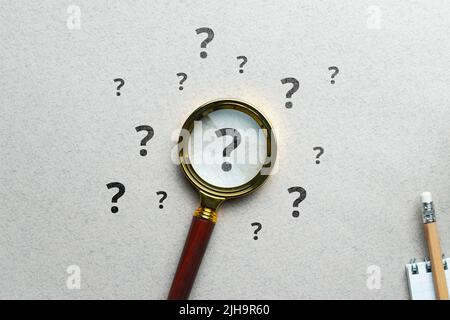 Question mark concept or FAQ. Sign under magnifying glass. Stock Photo