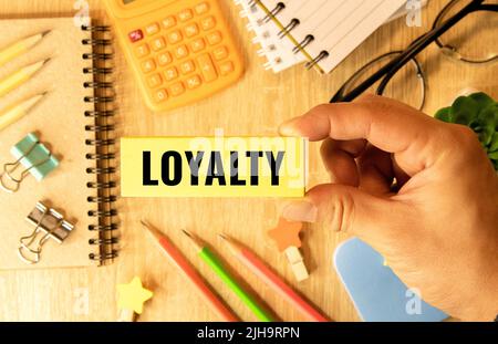 LOYALTY wood word on compressed board with human's finger at Y letter Stock Photo