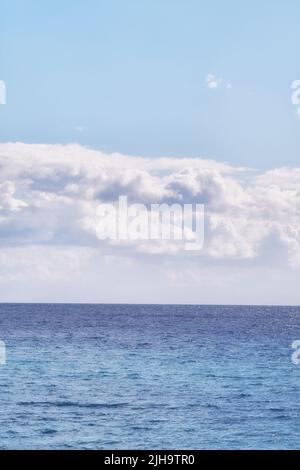 A cloudy blue sky and peaceful, calm ocean separated by a beautiful horizon with copy space. Deep blue water underneath a cloudscape skyline. The many Stock Photo