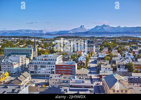 Aerial view of Bodo city in Norway on a sunny day with a blue sky. Scenic modern urban landscape of streets and buildings near a mountain horizon with Stock Photo