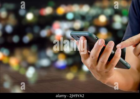 man using mobile phone in the street in the background night light. Stock Photo