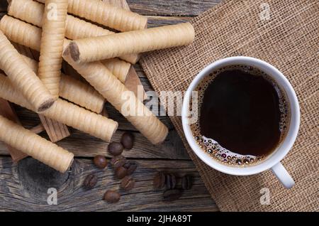 Chocolate waffle rolls and cup of coffee on rustic table, top view Stock Photo