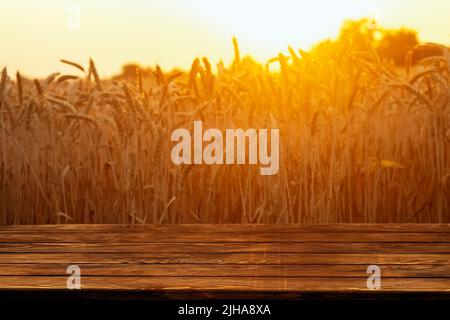 wooden empty table and golden ripe wheat field on sunset as background Stock Photo