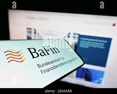 Smartphone with logo of German financial supervisory authority BaFin on screen in front of website. Focus on center of phone display. Stock Photo