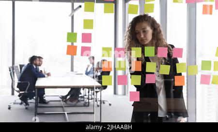 Busy focused businesswoman writing memos on paper notes Stock Photo