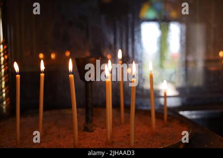 burning candles in the sand in a church Stock Photo