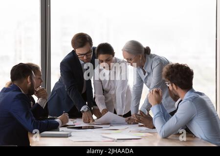 Serious diverse business group discussing project reports at meeting table Stock Photo