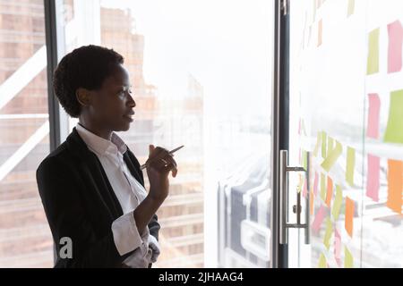 Engaged young African businesswoman working on project alone in office Stock Photo