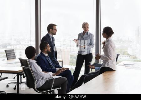 Confident mature female business leader holding meeting, training Stock Photo