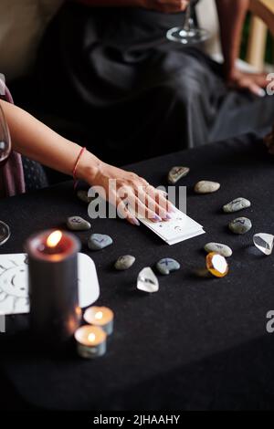 Young woman using tarot cards and rune stones for divination practice at home Stock Photo