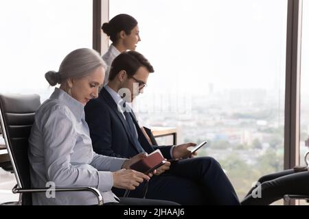 Serious diverse employees using work app on mobile phones Stock Photo