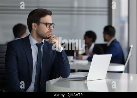 Thoughtful millennial businessman in glasses working at laptop Stock Photo