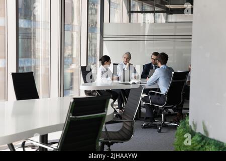 Diverse busy business group meeting at table, working on project Stock Photo