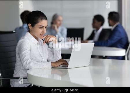 Focused busy young Indian worker using computer in co-working space Stock Photo