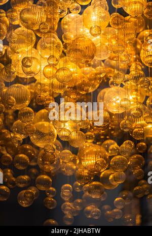 Lighting balls on the chandelier in the lamplight, light bulbs hanging from the ceiling, lamps on the dark background Stock Photo