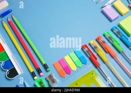 School supplies, colored pencils and watercolor paint pens, sticky notes on a blue background. Back to school creative, mockup concept. Stock Photo