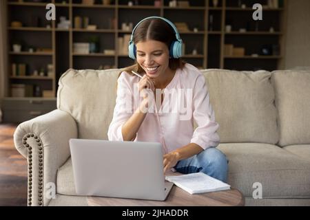 Young woman wear headphones using laptop studying online at home Stock Photo
