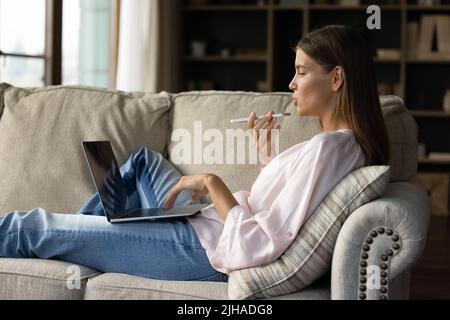 Woman make call talks on speakerphone and using laptop indoor Stock Photo
