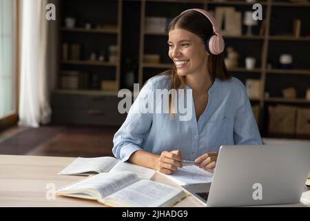 Woman wear headphones studying, prepare for exams use laptop Stock Photo