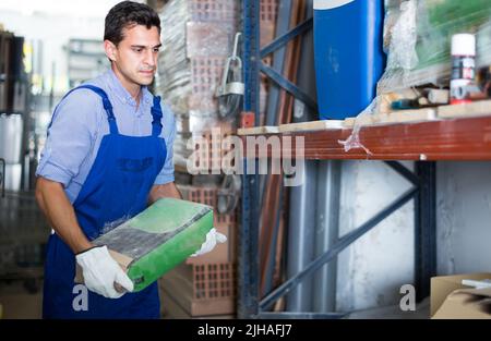 young male in uniform is choosing cement in the building store Stock Photo