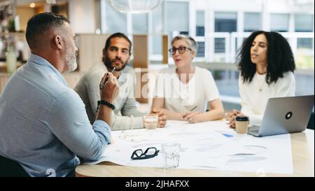 Group of design professionals having a discussion during a meeting in the office. Team of innovative businesspeople sharing creative ideas while worki Stock Photo