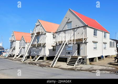 Tollesbury Essex row of weather boarded historical one time sail lofts now for small business use despite steps & ladders required above high tides UK Stock Photo
